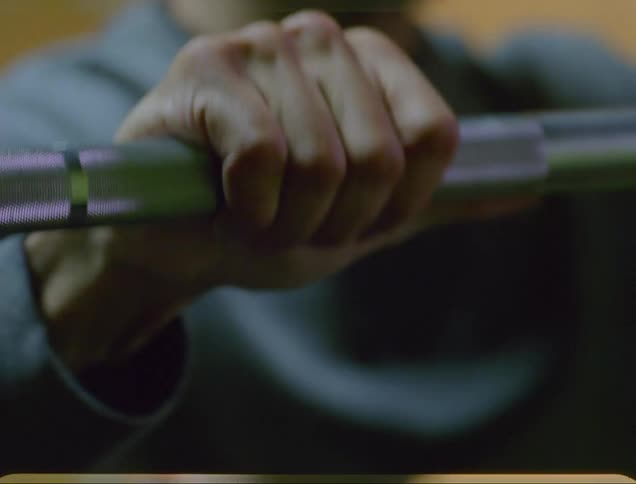 A man grips a barbell as he lifts weights