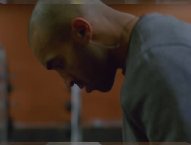 A man shadow boxing and exercising in a gym while wearing headphones