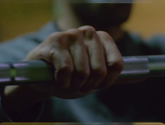 A man grips a bar bell as he lifts weights