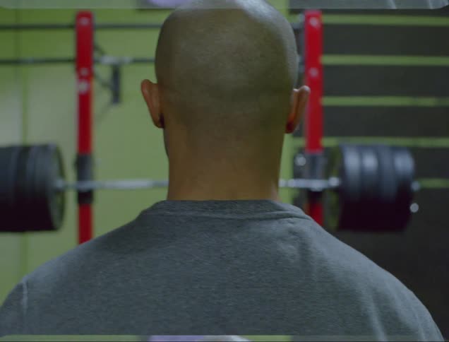 A man psyches himself up as he prepares to lift barbells in a gym
