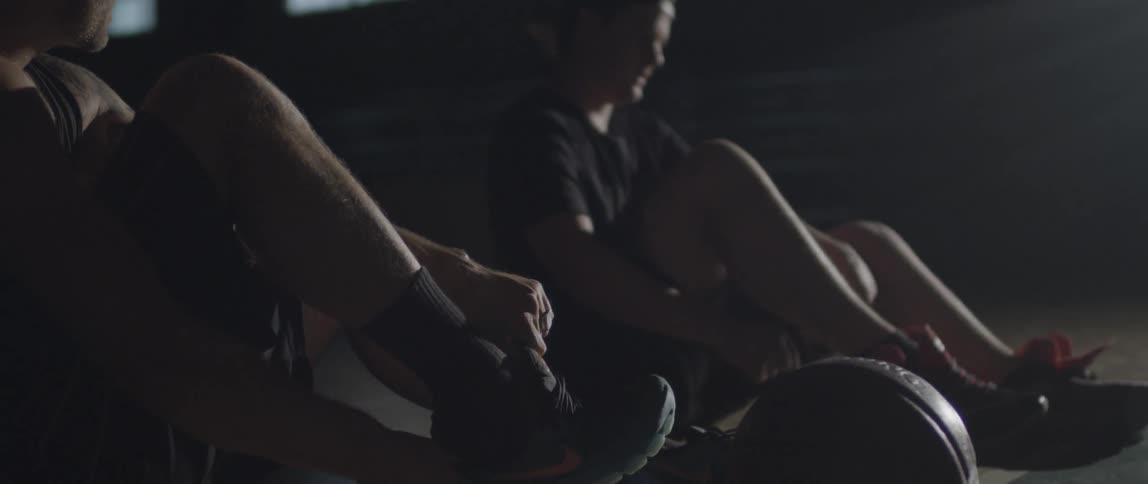 Men sit on a gymnasium floor and put on their shoes