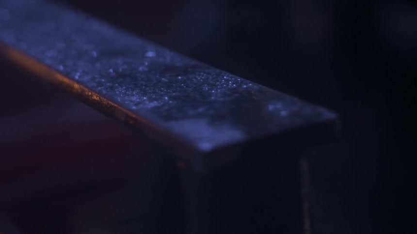 A metal beam sits in a dark room