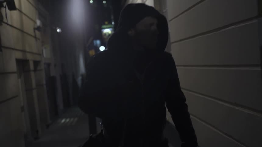 A man carrying a bag is walking in an alley
