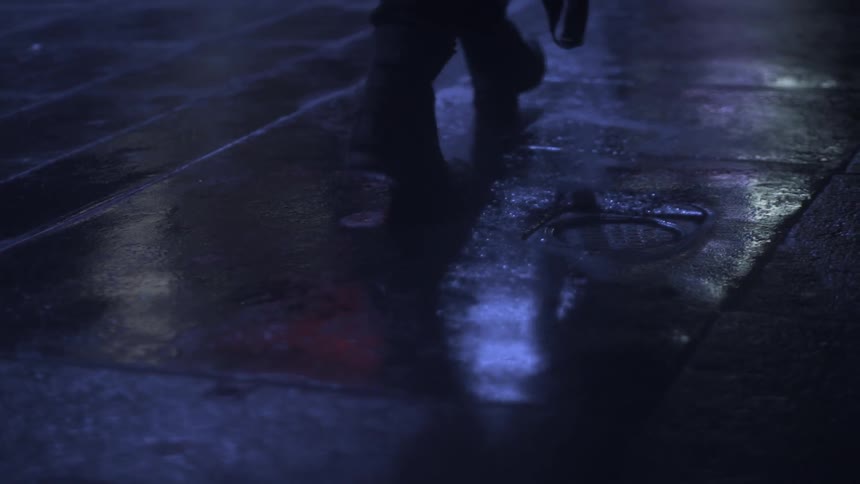 A person walks on a sidewalk at night