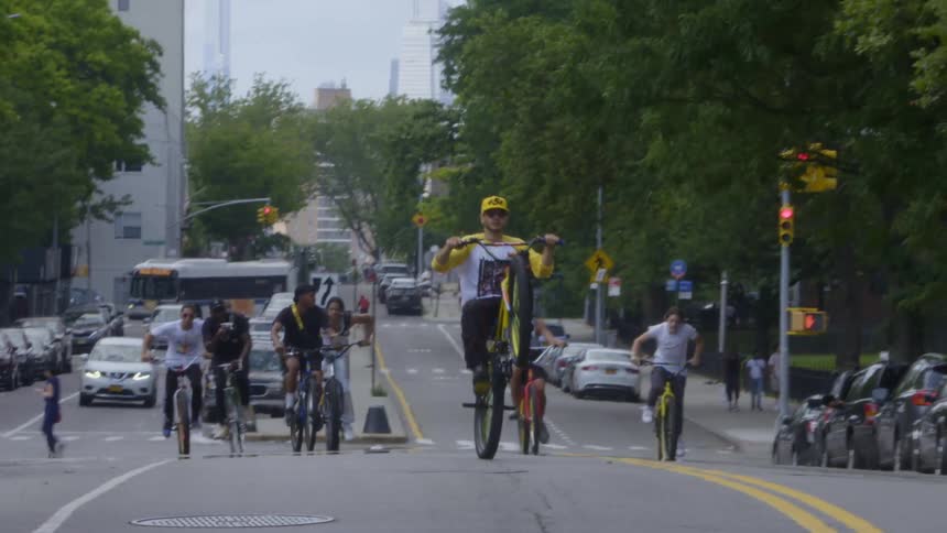 A group of young people are riding bikes in the middle of a city street