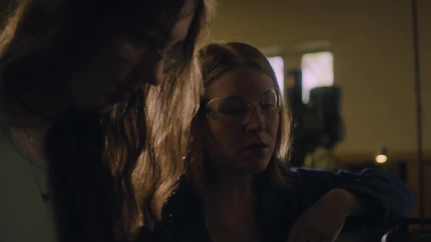 Two women in the workshop with one wearing protective glasses while talking to each other