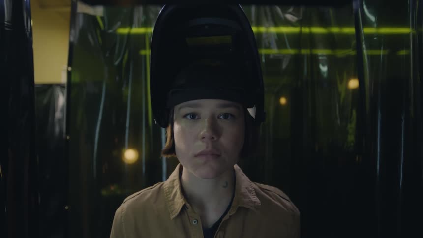 Woman removes the helmet covering her face and looks intently at the shot