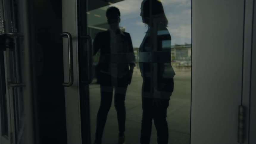 Reflection of two women walking through a glass door