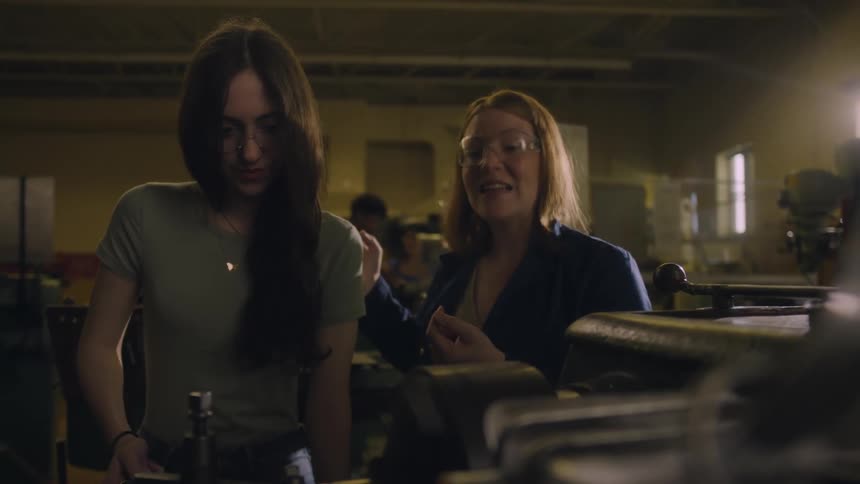 Woman teaching teenage girl how to use a machine that spins