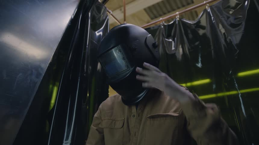Welder finishes welding and pushes her face shield up