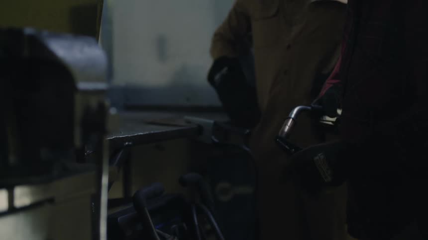 Two people stand together while one tries to light their welding torch