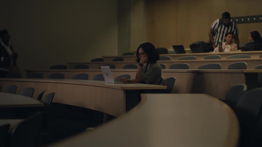 Teacher approaches a student sitting on a lecture hall