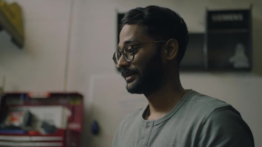 A man wearing glasses smiles and nods while he is talking