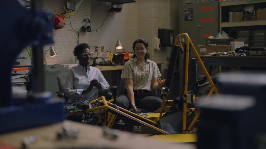 Two women working together in industrial lab smile pleased at results