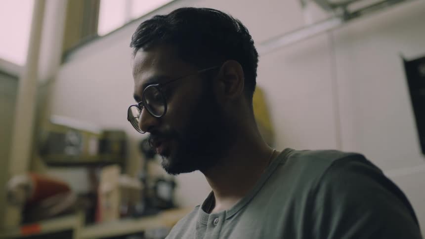 Up close of a man wearing glasses standin in a studio talking to someone