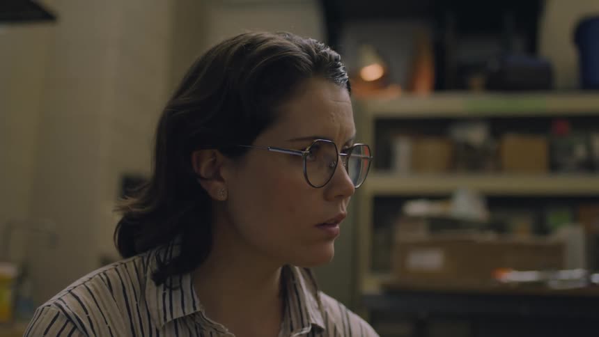 Woman works in dimly lit office with full bookcase in the background