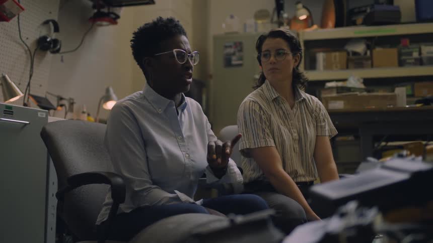 A caucasian and a black woman sitting in a room talking