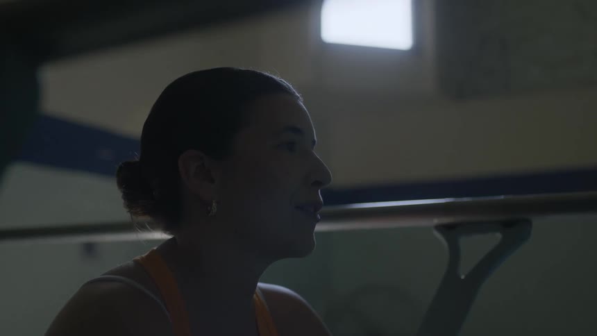 Woman smiles and talks while sitting between hand rails in gym