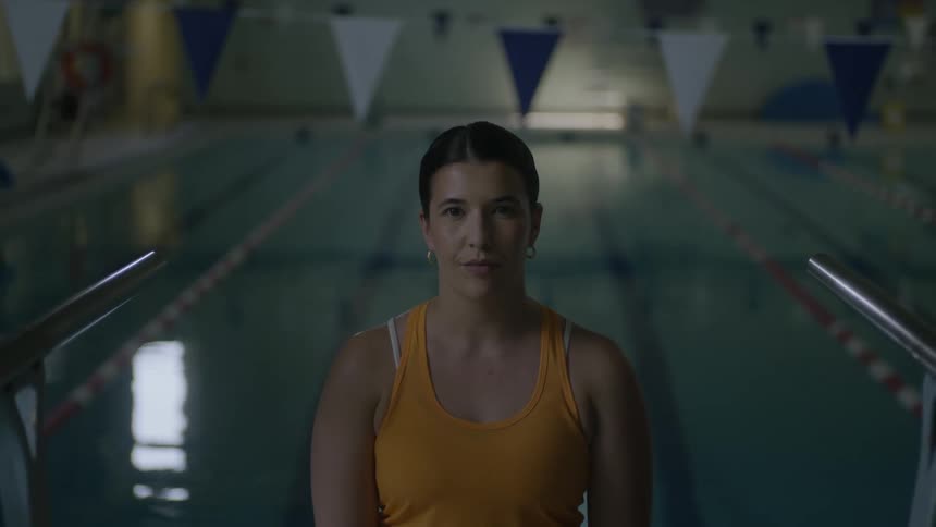 Woman in yellow bathing suit standing next to a swimming pool
