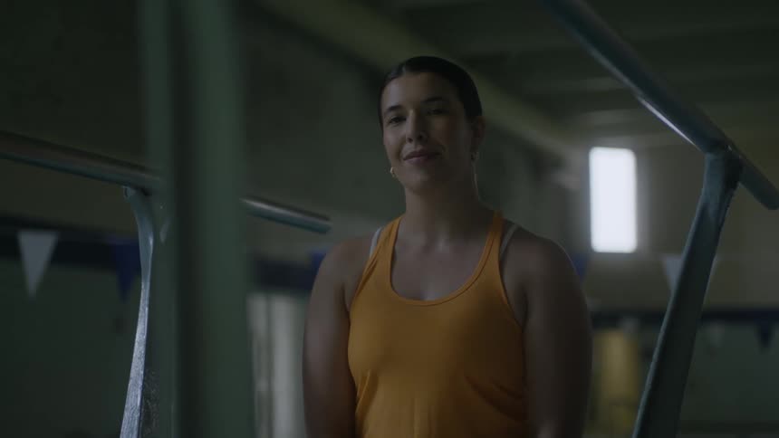 Woman smiles while posing between hand rails of diving platform
