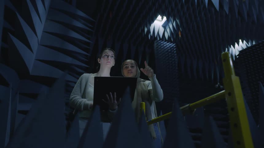 Two women talking and looking to have a laptop in a modern office building