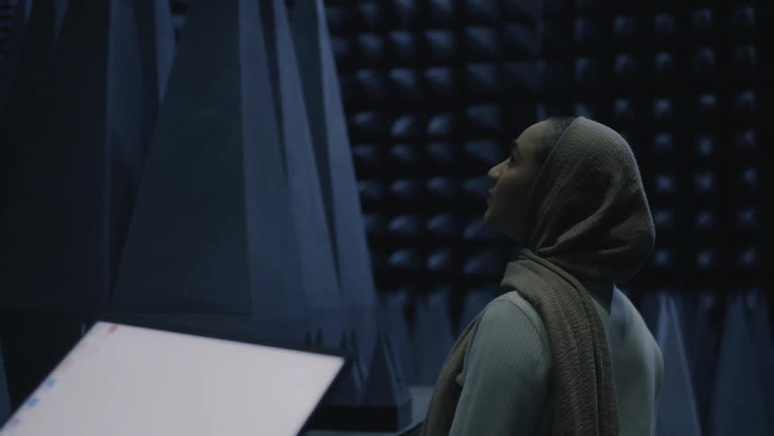 Woman looks at the padded walls of a recording booth