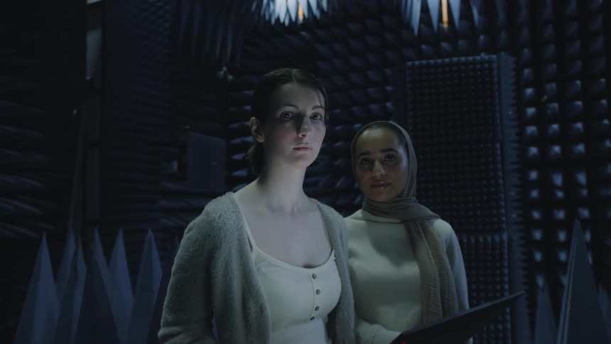 Two women stand in the middle of a recording booth