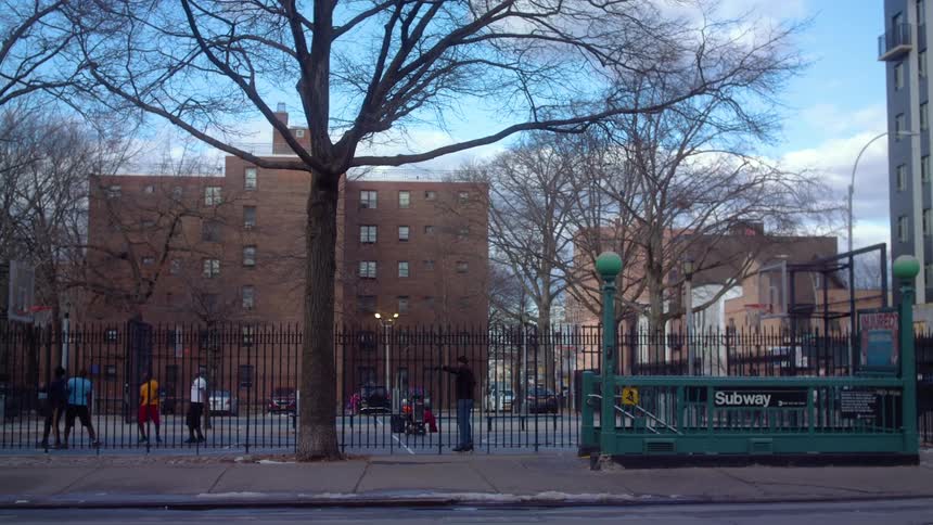 People play basketball at court behind the fences