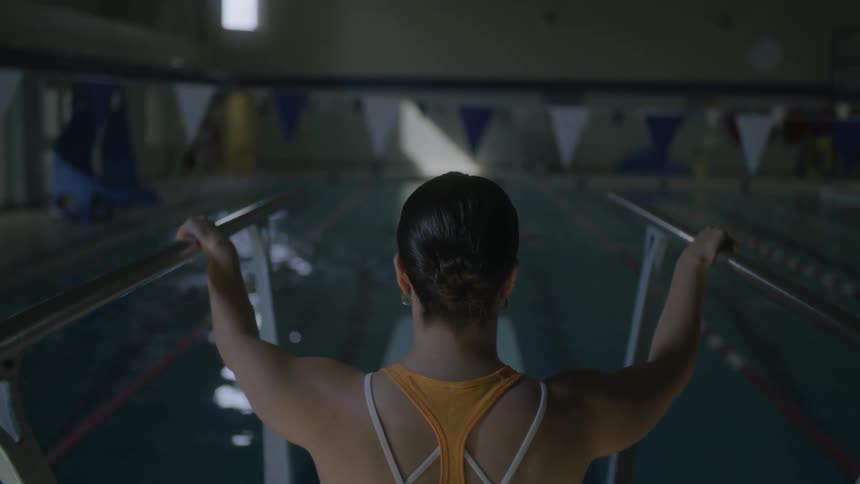 A female swimming coach sits and watchers swimmers in a pool