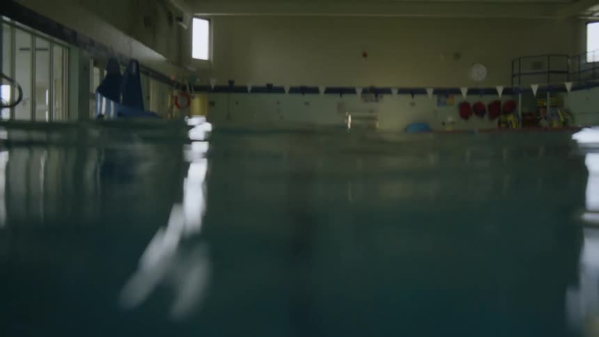 From under the swimming pool rising slowly above it is a room with low light