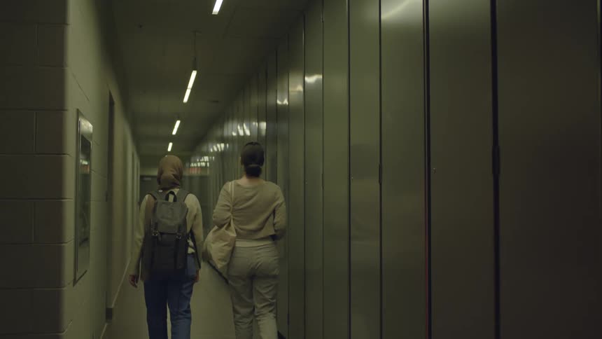 Two young women walk down a hallway in the university dorms