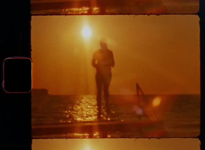 Dark silhouette of female fitness coach working out during Pilates training session jogging or running in place doing skippings with high legs and knees on a pier at the ocean in front of the sun on a sunny spring morning with golden light on vintage film
