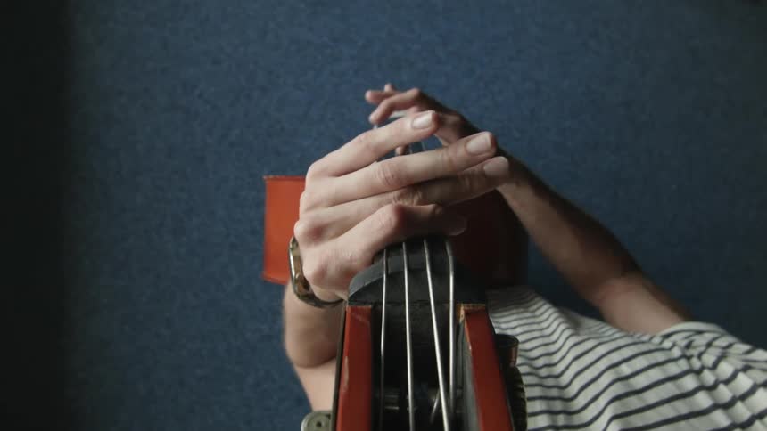 A man plays an upright string bass and playfully spins it around