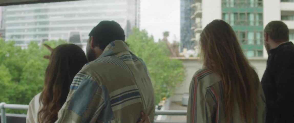 Group of friends looking at the rain out the balcony of a parking garage in the city
