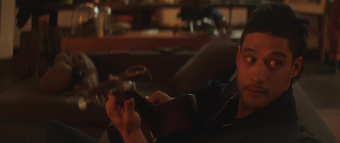A man is sitting on a couch and playing the guitar