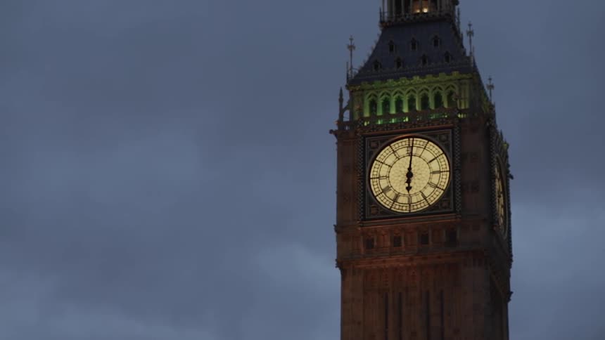 A clock tower is lit at sunset