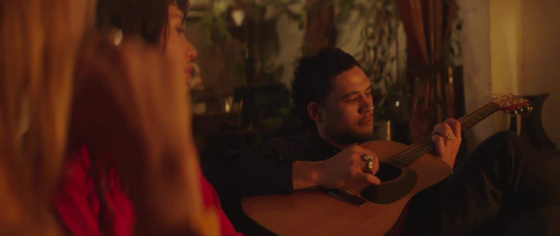 A group of friends are hanging out and playing the guitar