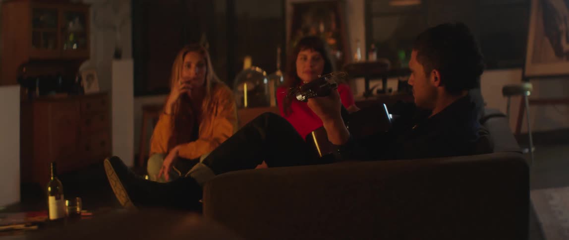 A group of friends are talking to each other and sitting on a couch
