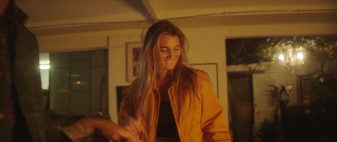 A woman dancing with a man picks up a drinking glass while continuing to dance