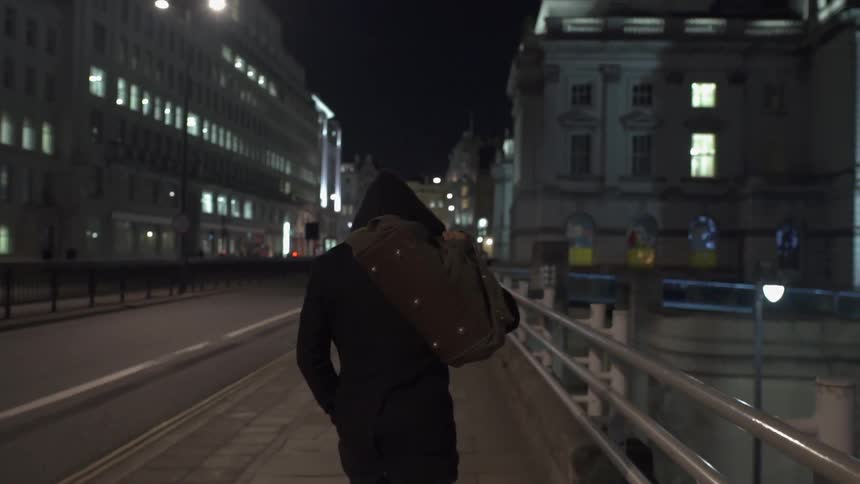 A man carrying a bag over his shoulder as he walks in the city