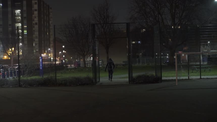 A man pushes open a gated fence and walks through