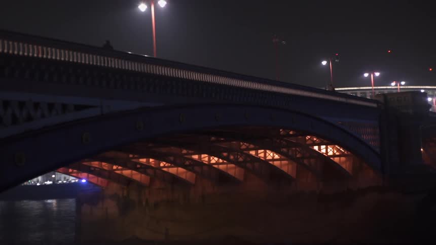 A pedestrian is walking across a bridge at night