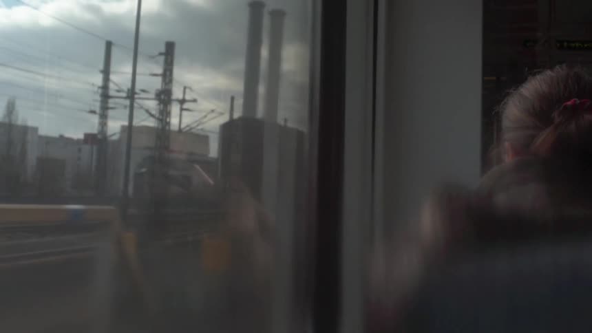 A woman is riding on a train in an industrial area