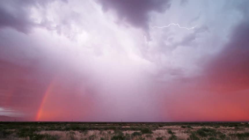 On a cold evening the sky turns red as thunder and lightning illuminate the clouds casting an eerie glow over a green field with leaves transitioning to vibrant autumn colors