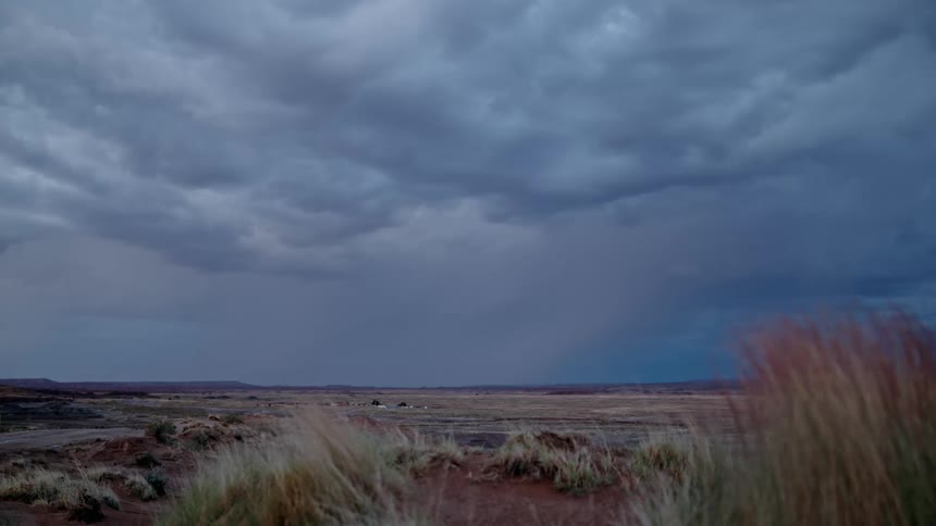 On a cloudy evening in the wilderness a thunderstorm brews with frequent lightning strikes illuminating the darkened skies