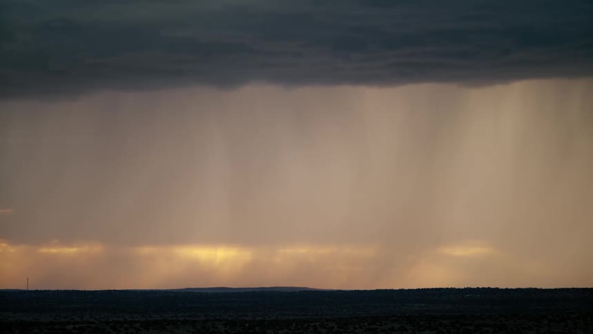 A lightning and thunderstorm lighting up the gray sky as rain washes across the landscape