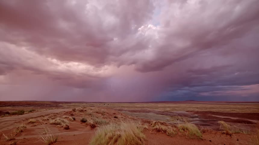 Lightning in a huge cloud with pink color in the middle of the desert