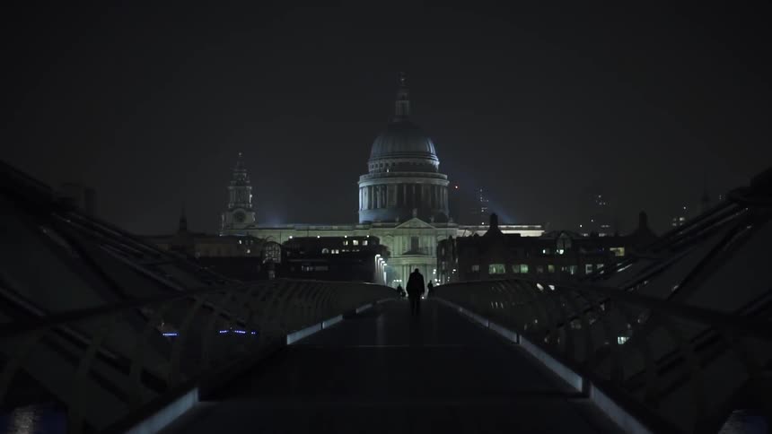 A large building lies ahead as someone walks at night