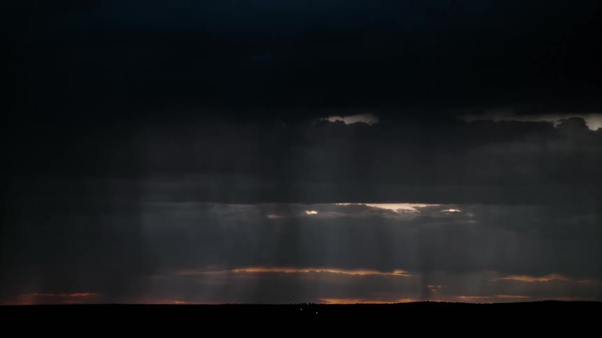 Lightning and thunder storm in a cloudy sky with sunlight between the clouds