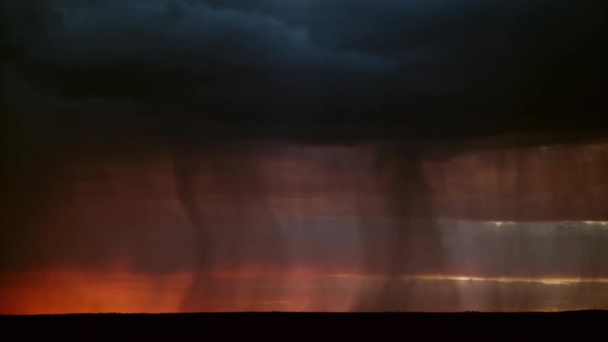 Lightning and rain from a thunderstorm fall over the plains at evening